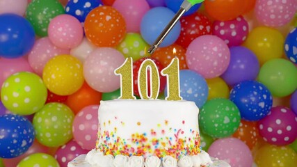 Cake with burning candles number 101. A tasty Birthday Cake on a bright festive background of colorful balloons.