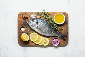 Fresh dorado on a cutting board with lemon and spices.
