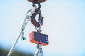 An orange plastic square portable measuring scale for fish and hunting hangs from a large slip...