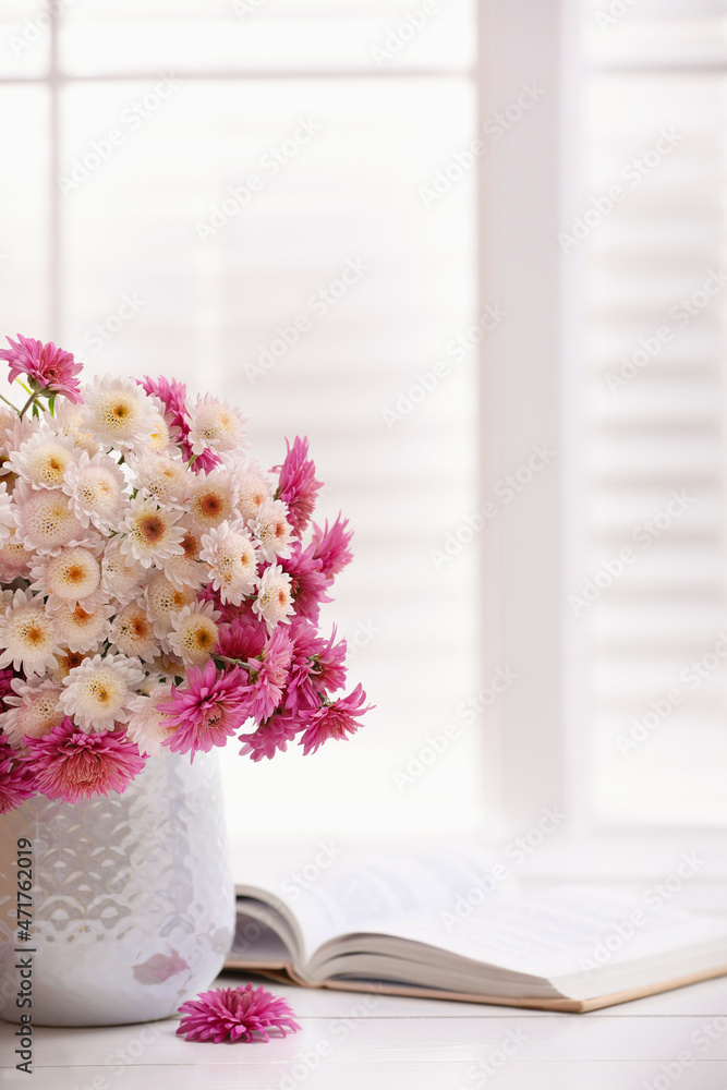 Wall mural Beautiful bouquet and open book on white wooden table near window