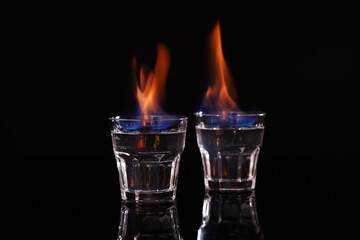 Flaming vodka in shot glasses on black background