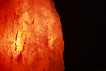 Himalayan salt lamp on dark background, closeup. Space for text