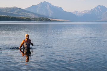 Blonde adult woman enjoys taking a dip in the cold waters of Lake McDonald in Glacier National Park...