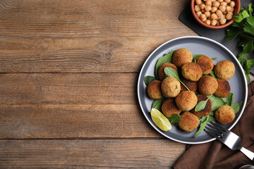 Delicious falafel balls with lime on wooden table, flat lay. Space for text