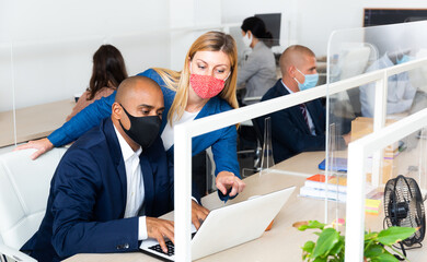 Businesswoman in protective mask explaining something to male coworker