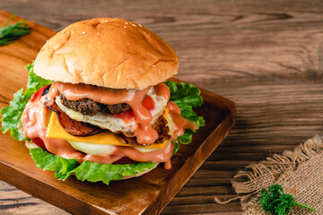 Fresh grilled homemade burgers with beef, tomato, fried egg, cheese and lettuce on rustic wooden background. fast food and junk food concept. fresh tasty burger on dark background.