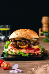 Fresh grilled homemade burgers with beef, tomato, fried egg, cheese and lettuce on rustic wooden background. fast food and junk food concept. fresh tasty burger on dark background.
