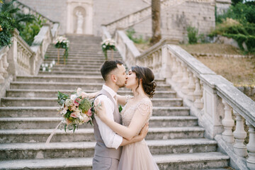 Bride kisses groom on the stone steps near the old villa