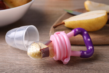 Nibbler with fresh apple on wooden table. Baby feeder