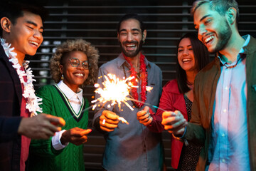 Smiling young multiracial friends having night party with sparklers.