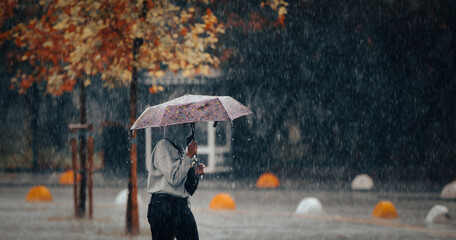 woman holding umbrella walking in rainy weather