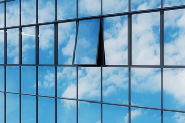 Open glass window with reflection sky on high rise building