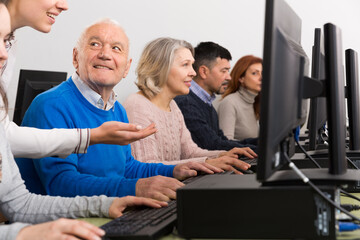 Obraz premium Serious businesswoman helping to man, pointing at computer monitor in office