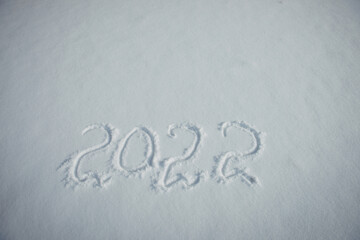 Drawing on white snow. New Year's date, figures 2022, close-up.