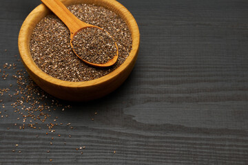Bowl of organic natural chia seeds close-up on wooden background or table