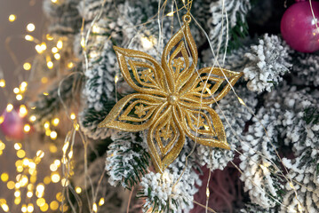 Golden snowflake on a branch of an artificial Christmas tree close-up. Details of Christmas tree.