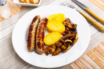 Delicious pork sausage with roasted mushrooms and potatoes on a plate in a restaurant