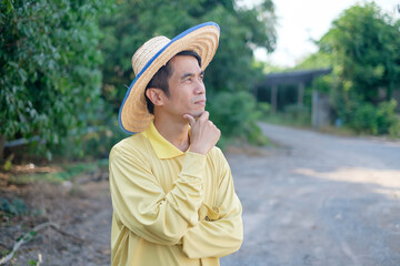 Asian farmer wear yellow shirt pose thinking or confuse at farm