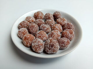 Tamarind candy, placed inside white small plate. Sweet and sour candy made from tamarind paste and coated by sugar.