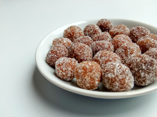 Tamarind candy, placed inside white small plate. Sweet and sour candy made from tamarind paste and coated by sugar.