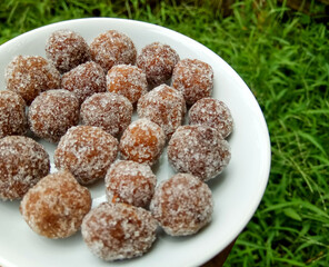 Tamarind candy, placed inside white small plate. Sweet and sour candy made from tamarind paste and coated by sugar.