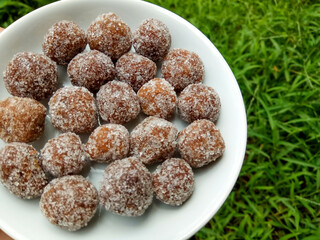 Tamarind candy, placed inside white small plate. Sweet and sour candy made from tamarind paste and coated by sugar.