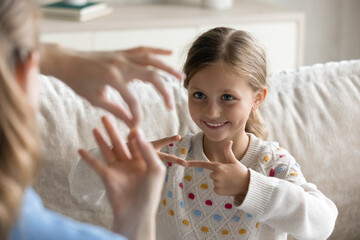 Smiling cute little preschool child girl with hearing disability making gesture with fingers,...