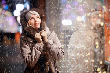 happy girl lights evening christmas shopping standing on the street by the shop window