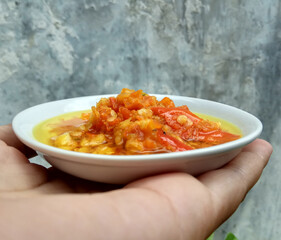 Sambal matang or traditional chili sauce from Indonesia, roughly crushed and cooked by hot oil. Placed in a white small plate.