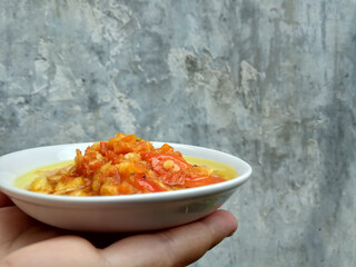 Sambal matang or traditional chili sauce from Indonesia, roughly crushed and cooked by hot oil. Placed in a white small plate.