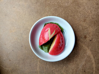 Ang ku koe, or Red Tortoise Cake, is a Chinese traditional cake. Also popular in Indonesia as Kue Ku. Red chewy skin with mung bean paste inside. In white small plate, on wooden table