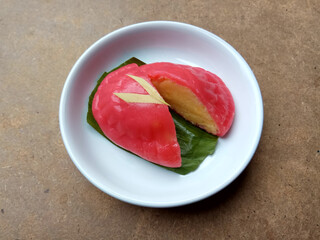 Ang ku koe, or Red Tortoise Cake, is a Chinese traditional cake. Also popular in Indonesia as Kue Ku. Red chewy skin with mung bean paste inside. In white small plate, on wooden table