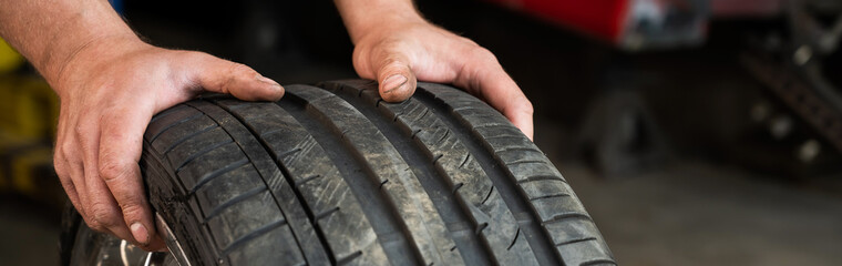 An auto mechanic holds a wheel of a car. Change of car tires according to the season