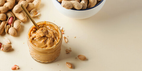Glass jar of homemade peanut butter on kitchen table banner with space for design