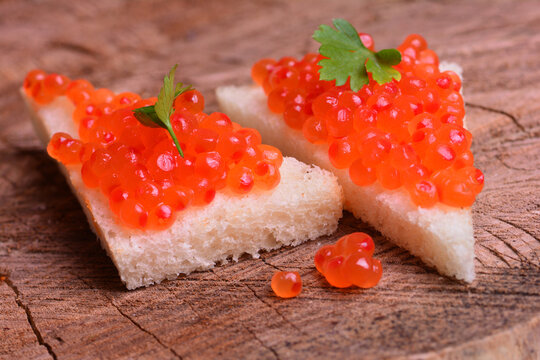 Bread with red caviar on a wooden background