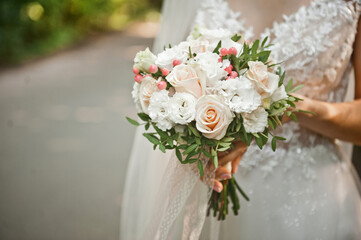 Embracing the hands of the newlyweds with a bouquet of beautiful flow