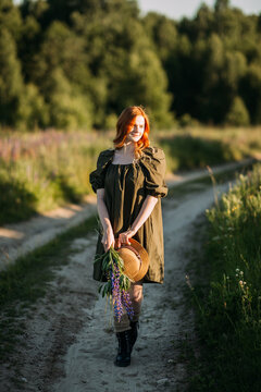 A village red-haired girl walks along a rural road in summer 3290.
