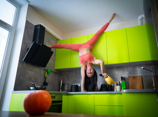 Flexible woman cooking upside down in kitchen. Concept of individuality, creativity, handstand and self-confidence