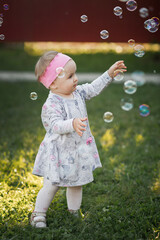 A little girl is sitting on a green lawn and admiring soap bubbles 3434.