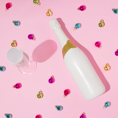 Creative pattern made with champagne glass, bottle and colorful Christmas baubles. Minimal pink New Year party background.