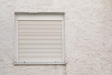 white closed window on a wall, white metal jalousie rolled up, no person, space for text
like lock...