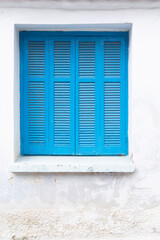 White painted wall with closed window, frame with blue shutter, 
space for text, lock down