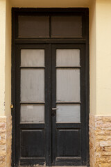 Obraz premium Closed old wooden door with glass in building, vertical format and no person
