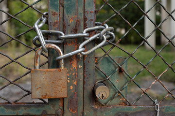 Lock down, old rusty padlock on a mesh fence with metal chain, safety first, no person 