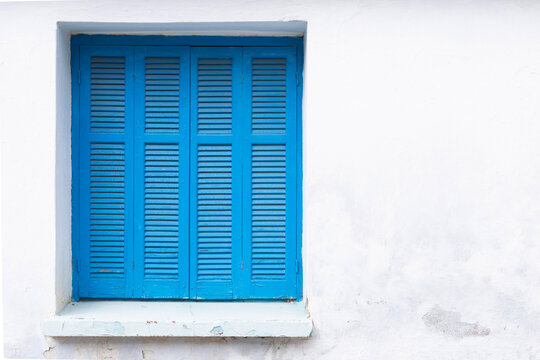 White painted wall with closed window, frame with blue shutter, 
space for text, lock down