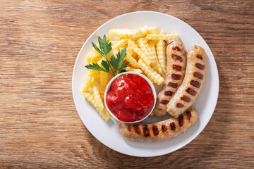 plate of grilled sausages and french fries, top view