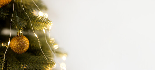 Close up of gold ball toy and garlands on green-yellow Christmas tree