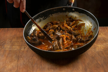 The cook prepares meat with vegetables and onion in a bowl . Oriental cuisine