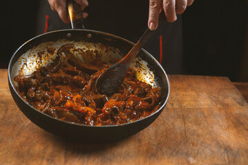 The cook prepares meat with vegetables and onion in a bowl . Oriental cuisine