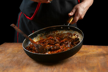 The cook prepares meat with vegetables and onion in a bowl . Oriental cuisine